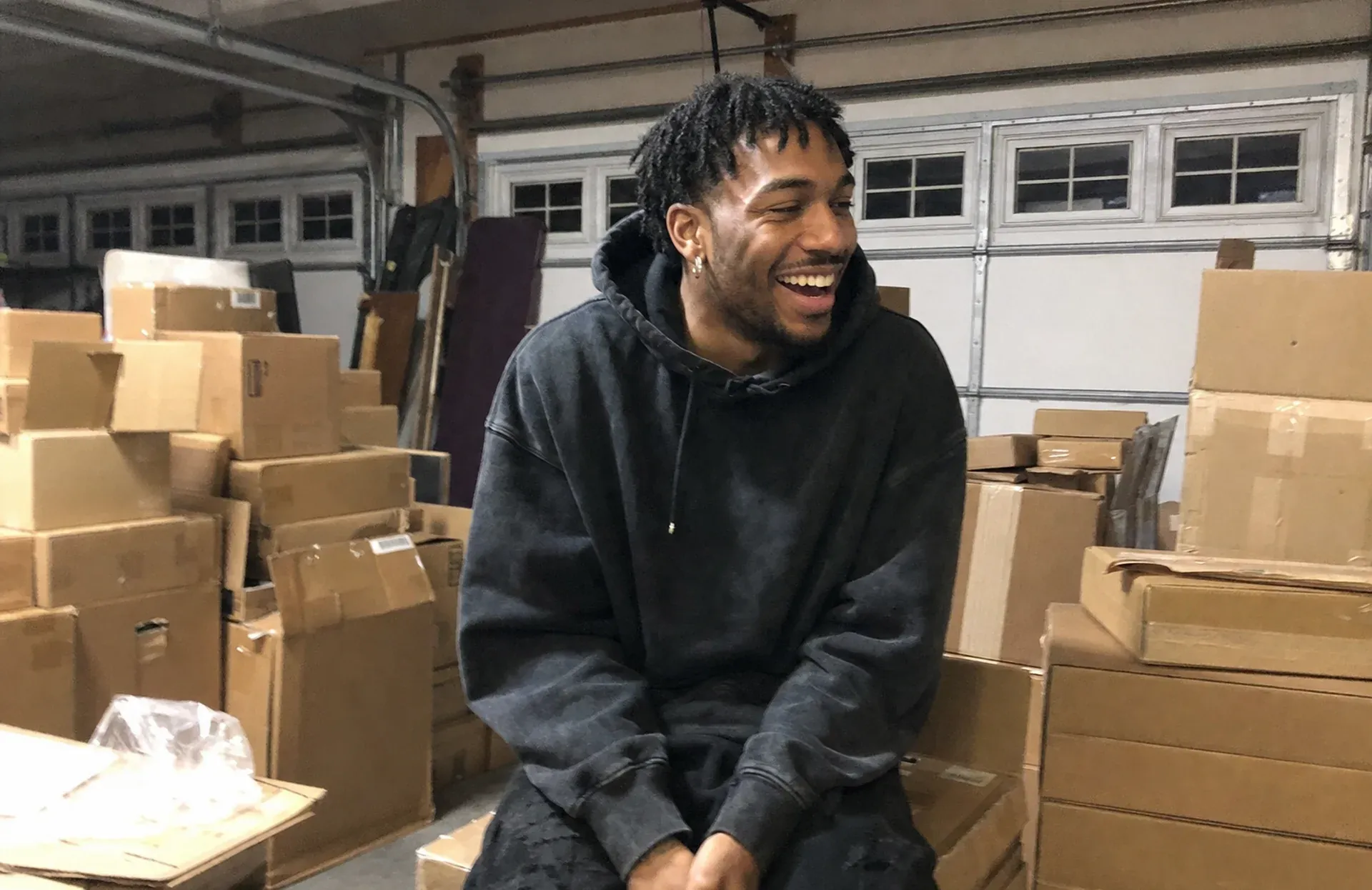 Marcus Reyes laughing in his garage, surrounded by boxes